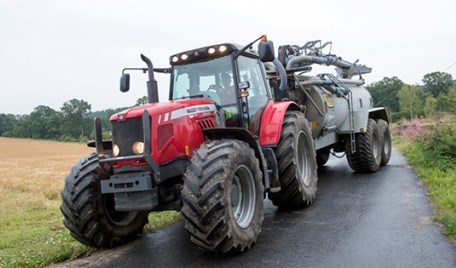 En stor röd traktor som kör på en grusväg.