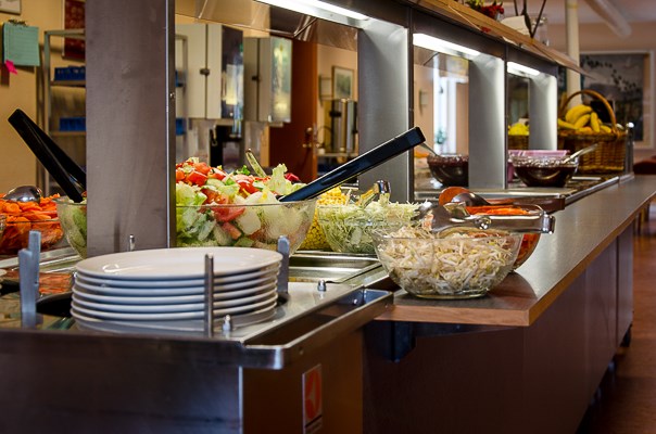 En salladsbuffé med flera glasskålar med sallad och grönsaker.