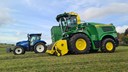 En självgående exakthack av märket JD 8100 bredvid en mindre blå traktor  under skördearbetet ute på fälten vid  Tenhults naturbruksgymnasium.