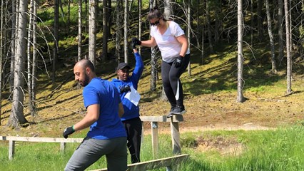 Tre personer gör samarbetsövningar ute i naturen.