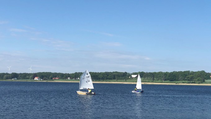 Två segelbåtar seglar på sjön. Himlen är blå.