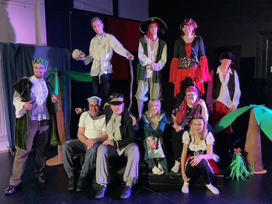 Tio utklädda människor vid en teaterscen. 