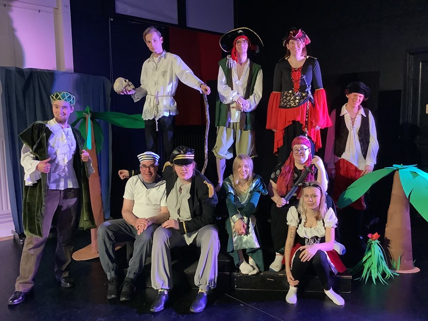 Tio utklädda människor vid en teaterscen. 