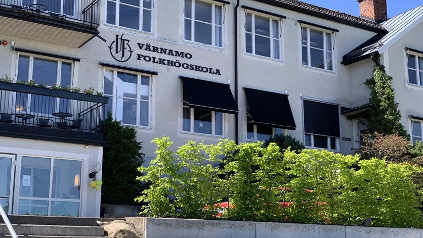 Vit skolbyggnad dekorerad med ballonger utanför entrédörrarna.