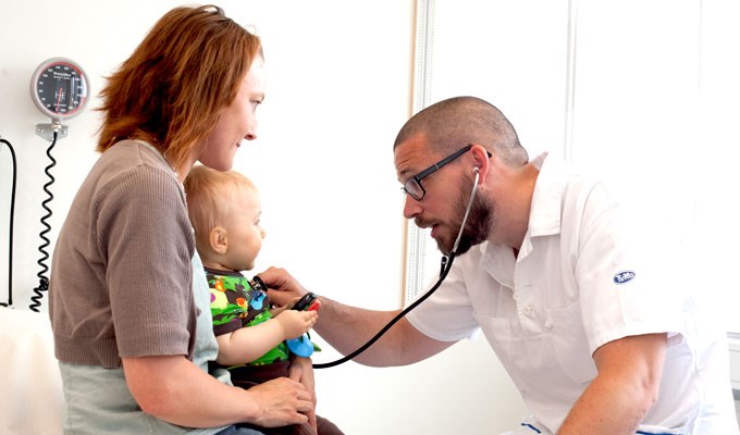 Läkare som undersöker barn i mammans famn