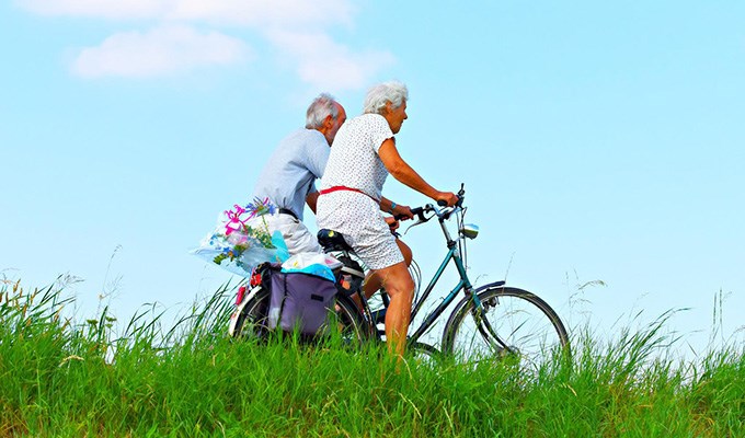 Äldre par cyklar i naturen en sommardag 